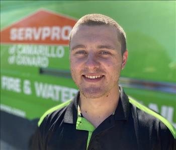 Portrait of Garrett, male employee in front of green truck